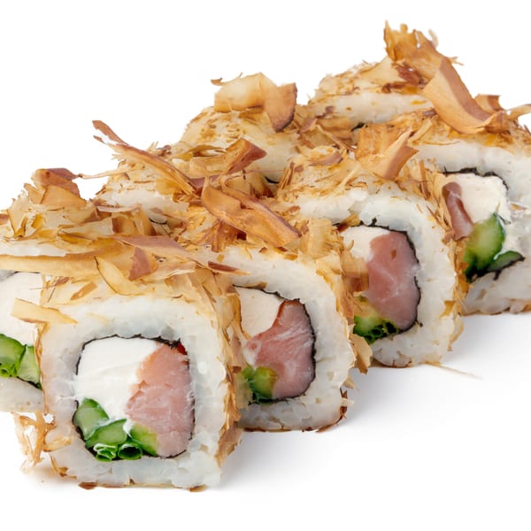 Four sushi rolls with salmon, cream cheese, and cucumber, topped with bonito flakes.